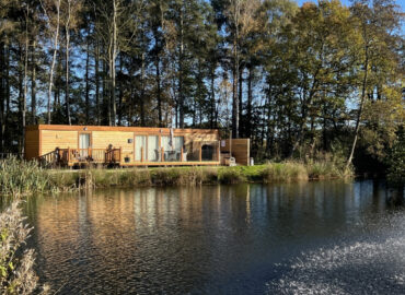Rowan Boutique Lodge overlooking serene lake, surrounded by mature woodland, ideal for couples and dog-friendly stays at Woodland Lakes Holiday Lodges.