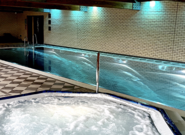 Indoor swimming pool and hot tub at Oaks 5* Health Spa, featuring tiled flooring, ambient lighting, and a tranquil atmosphere for relaxation.