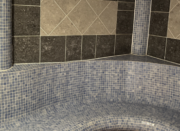 Mosaic tiled steam room seating area in luxury spa at Rowan Boutique Lodge, featuring blue and grey tiles for a relaxing experience.