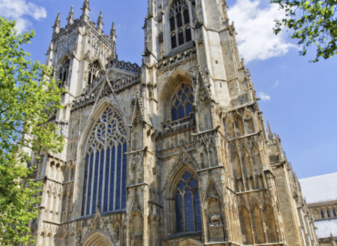 York Minster cathedral showcasing intricate Gothic architecture, large stained glass windows, and surrounding greenery.