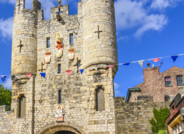 Historic stone castle with decorative banners, set against a blue sky, located in York, showcasing the city's rich heritage and charm.