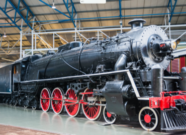Historic steam locomotive in a museum setting, showcasing black exterior and red wheels, representing heritage railway attractions.