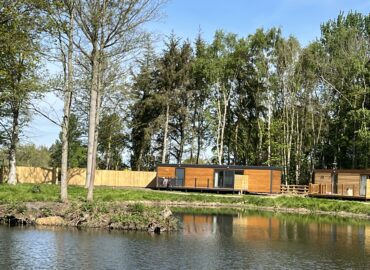 Rowan Boutique Lodge overlooking a tranquil lake, surrounded by mature woodland, showcasing luxury dog-friendly accommodation for couples.