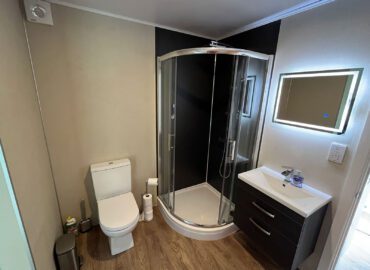 Modern bathroom featuring a shower cubicle, toilet, and sleek vanity unit with a mirror, designed for luxury lodge accommodation.