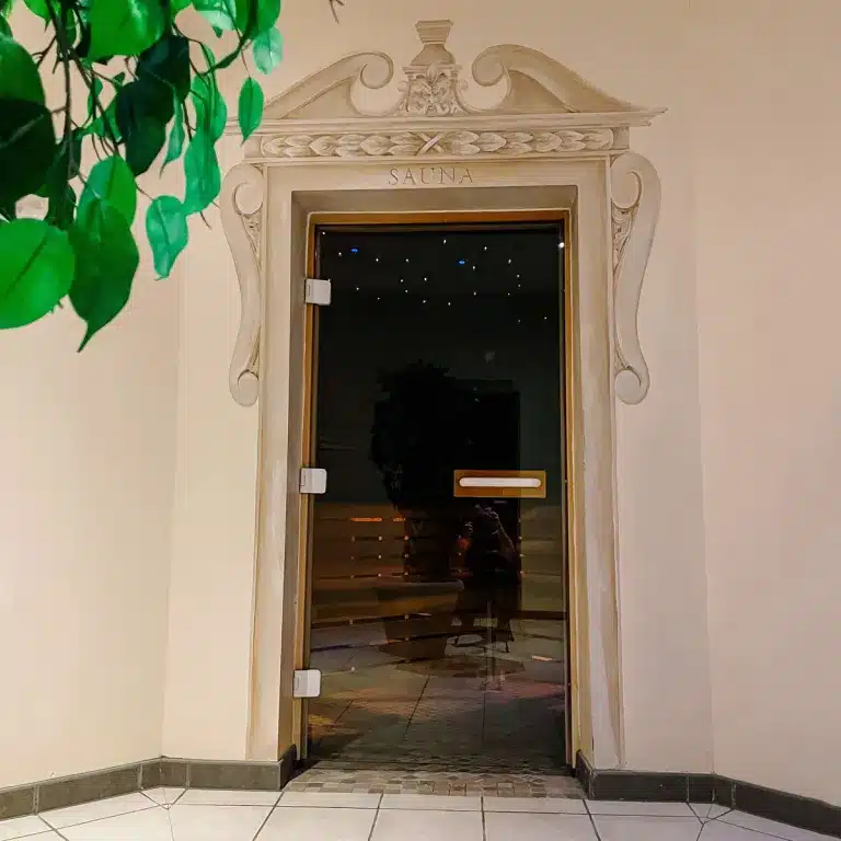 Sauna entrance with decorative archway, surrounded by greenery, highlighting spa facilities at Woodland Lakes Holiday Lodges.